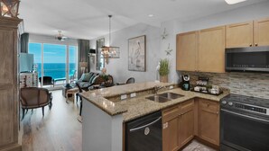 A modern kitchen with granite countertops, stainless steel appliances, and wooden cabinets. - 2306 - Nautical Style Couples Retreat (Panama City Beach)