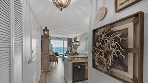 A modern kitchen with a central island, wooden cabinetry, and a view to the outdoors. - 2306 - Nautical Style Couples Retreat (Panama City Beach)
