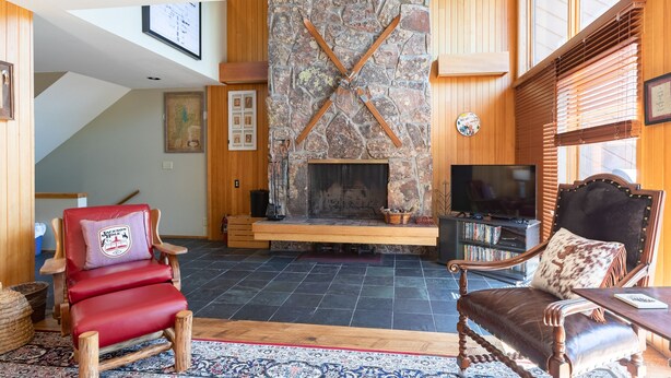 Ein gemütliches Wohnzimmer mit Kamin aus Stein, Holzmöbeln und einem Fernseher.