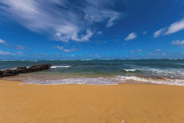 Una playa con cielos despejados y olas tranquilas.