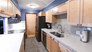 A compact kitchen with wooden cabinets, a stainless steel refrigerator, a coffee maker, and a sink. - JHRL - Teewinot D4, Great Slopeside Location (Teton Village)