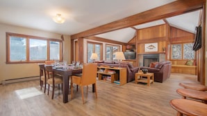 A spacious living area with a wooden dining table, a sofa, and a fireplace. - JHRL - Teewinot D4, Great Slopeside Location (Teton Village)