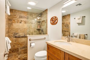 Een badkamer met douche, toilet, wastafel en spiegel.