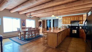 Une cuisine spacieuse dotée de meubles en bois, d’un îlot central et d’un coin repas avec une grande table et des chaises.