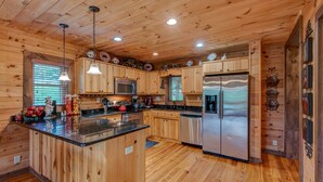 A wooden cabin interior with a kitchen featuring a central island, stainless steel appliances, and wooden cabinetry. - 1 Awesome Skyview - Spectacular log home with hot tub and  top of the line amenities! (Vilas)