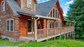 A log cabin with a porch and a deck, surrounded by greenery. - 1 Awesome Skyview - Spectacular log home with hot tub and  top of the line amenities! (Vilas)