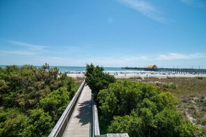 A wooden boardwalk leading to a beach with a pier and a covered structure in the distance. - $150 activities - E-gift card when you book - On the Beach | Spacious | 3 King Beds  | M2609 (Myrtle Beach)