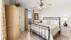 Een slaapkamer met een bed, nachtkastjes, een plafondventilator, een kledingkast en een raam met gordijnen.