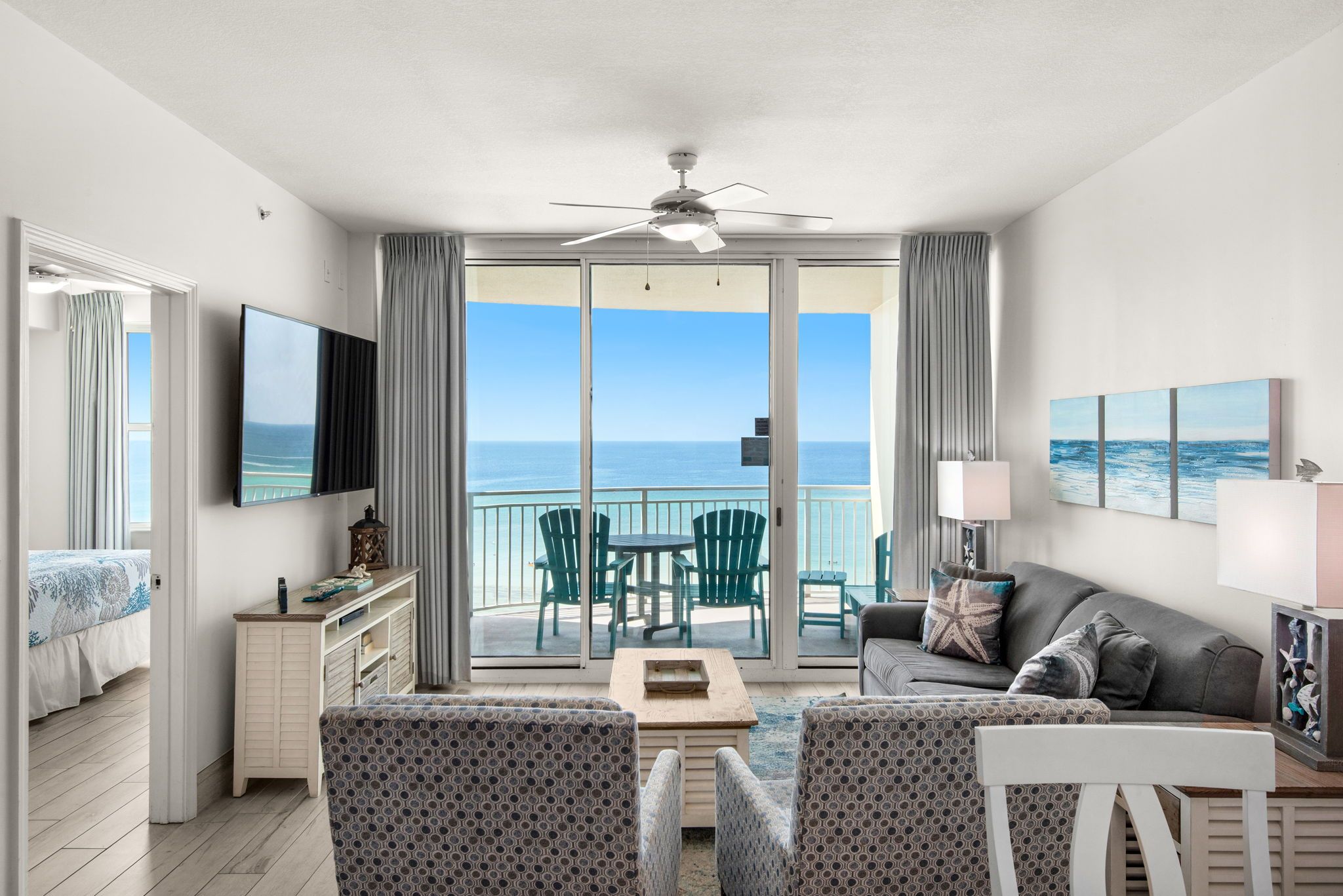 A hotel room with a balcony, a television, a sofa, and a dining table.