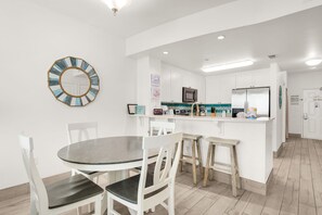 A modern kitchen with white cabinetry, a round dining table with chairs, and a central island with stools. - 506 - Beach Oasis Perfect for Families and Couples (Panama City Beach)