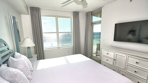 Ett hotellrum med en stor säng, en tv, en balkong med utsikt och en takfläkt.