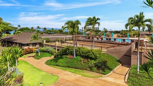Un resort con area piscina, palme e cielo sereno.