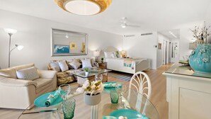 Un soggiorno moderno con un divano, un tavolo da pranzo con bicchieri e una ventola a soffitto.