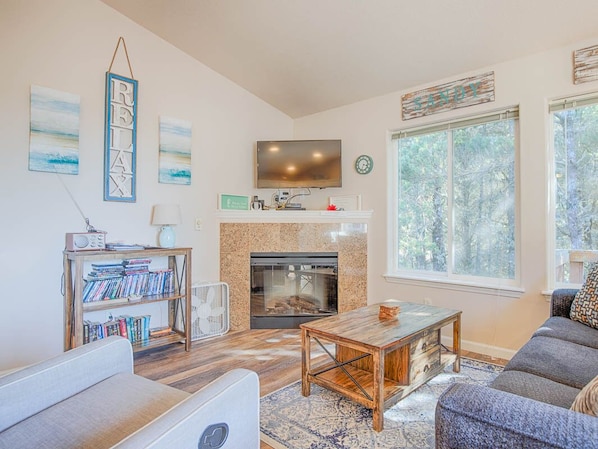 Una sala de estar con chimenea, televisor, estantería y sofá.