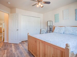 Une chambre à coucher avec un lit en bois, un ventilateur de plafond et une porte donnant sur une autre pièce.