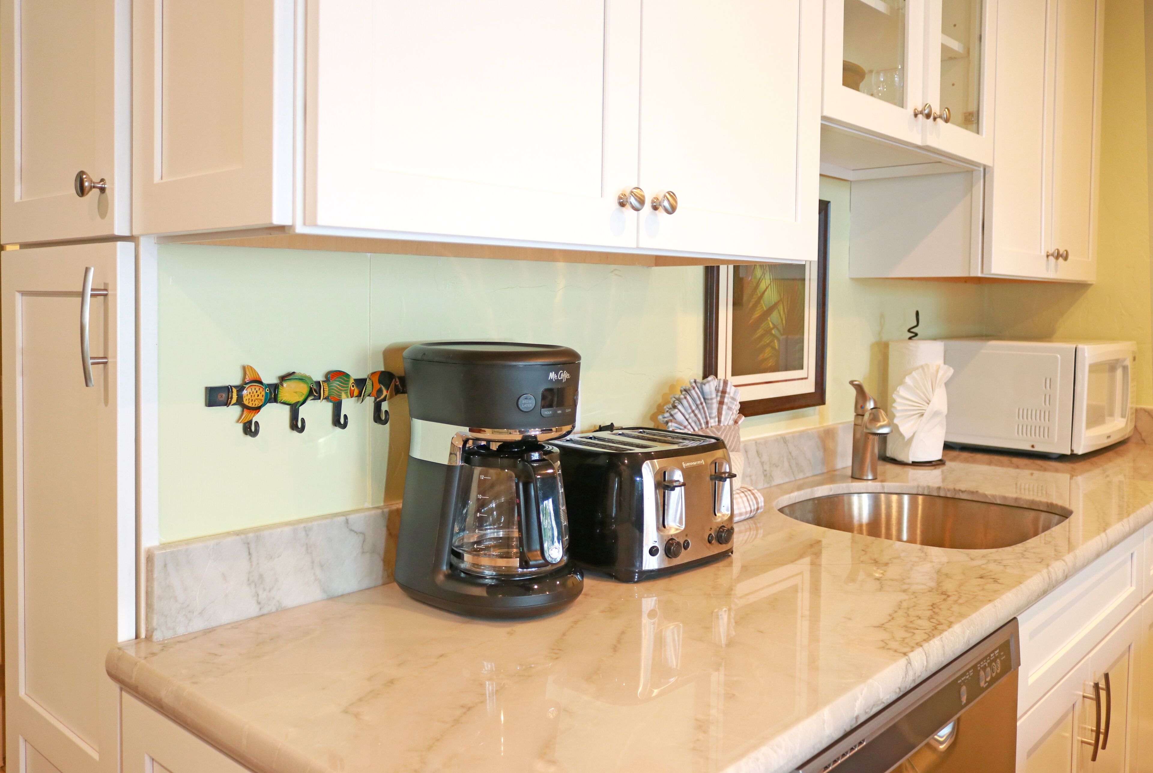 A kitchen with white cabinets, a coffee maker, a toaster, and a microwave.