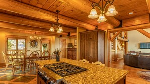 A spacious kitchen with a large island, wooden ceiling, and a dining area with chairs. - The Lodge - Theater Room, Putting Green, Pool, Great view 2 miles to Boone! (Boone)