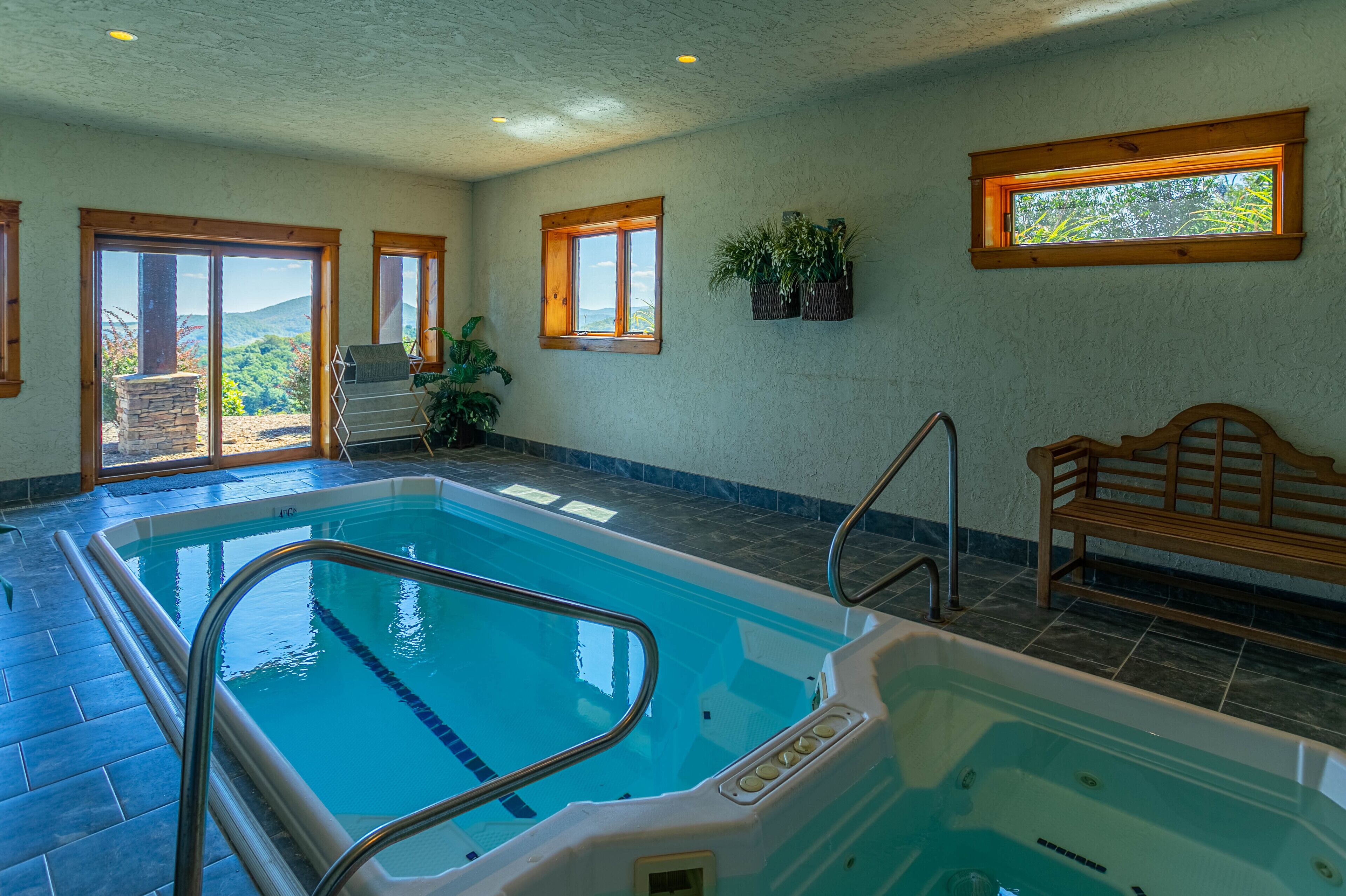 Ein Hallenbad mit Bergblick, einer Bank und einem Fenster mit Pflanzen.