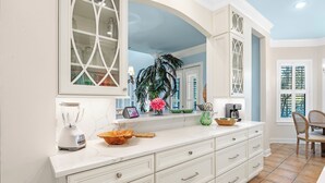 Una cocina con encimera blanca, una licuadora, un bol y una planta en maceta.