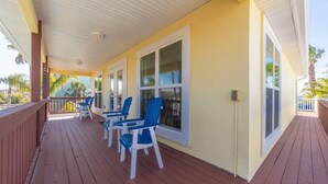 A covered porch with blue Adirondack chairs and a wooden deck. - Ocean View Pool Home ~ Heated Pool ~ Steps to the Beach! (Saint Augustine)