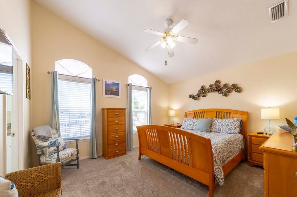 A bedroom with a bed, a nightstand, a dresser, a chair, and a ceiling fan.