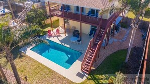 A two-story house with a swimming pool, a covered patio, and a fenced backyard. - Ocean View Pool Home ~ Heated Pool ~ Steps to the Beach! (Saint Augustine)