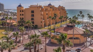 A resort with multiple buildings, palm trees, and a beach view.