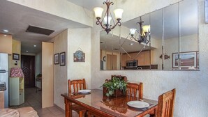 A dining area with a wooden table and chairs, a chandelier, and a large mirror above the table.