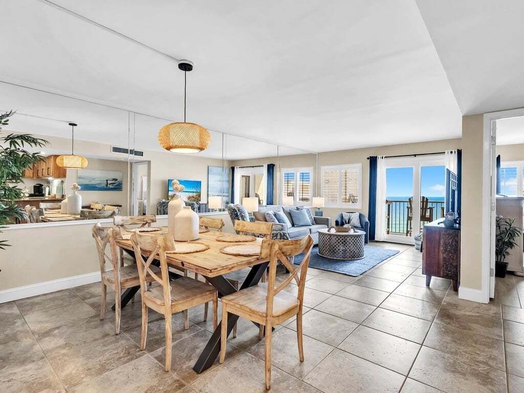 A spacious living area with a dining table, sofas, and a view of the sea.