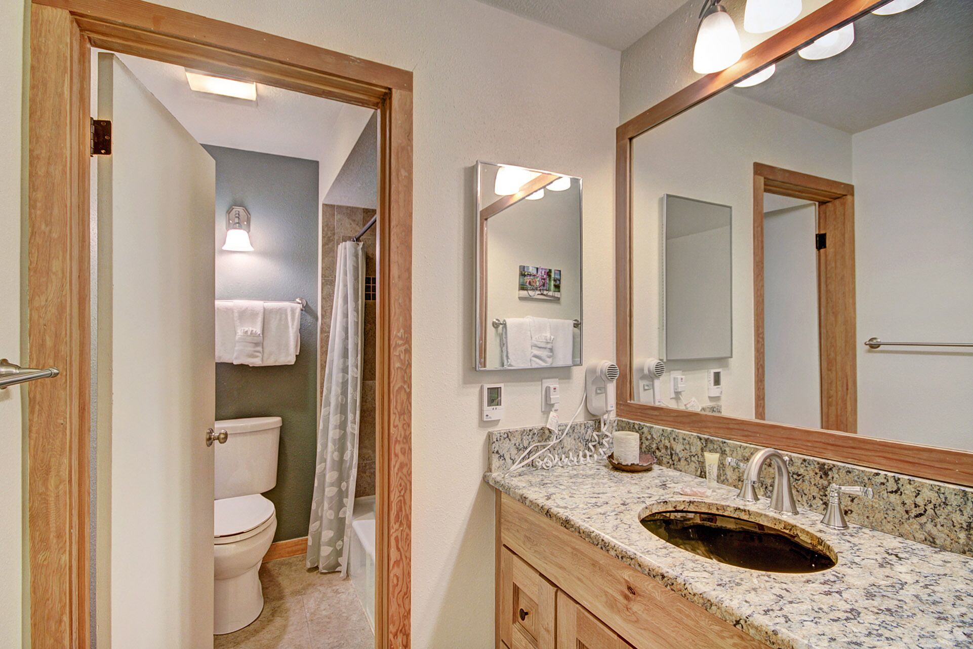 A bathroom with a toilet, shower, sink, and mirrors.