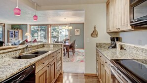A kitchen with granite countertops, wooden cabinets, a built-in oven, and pendant lighting.