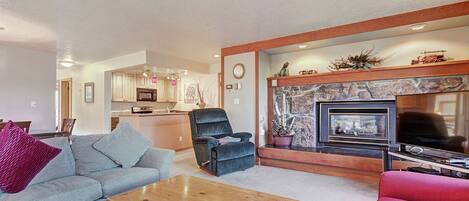 A living room with a fireplace, a sofa, a coffee table, and a television.