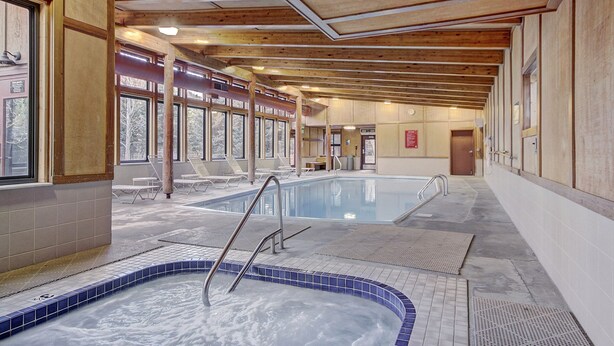 A spa area with two hot tubs, wooden ceiling beams, and a tiled floor.