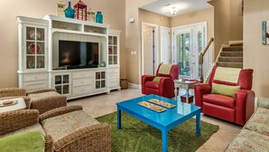 A spacious living room with a large white entertainment center, red leather sofas, and a blue coffee table.