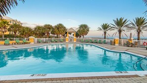 A swimming pool with a gazebo, palm trees, and a view of the ocean.