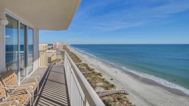 A balcony with a view of a beach and ocean.