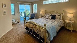 A bedroom with a large bed, a ceiling fan, a window with a view, and a small table with a lamp. - Heavenly Ocean View - #LH37: 2  BR, 2  BA House in Cambria, Sleeps 4 (Cambria)