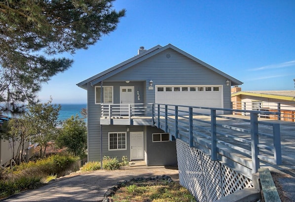 Une maison à deux étages avec un garage, un balcon et une vue sur l’océan.