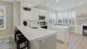 A modern kitchen with white cabinetry, stainless steel appliances, and a large island.
