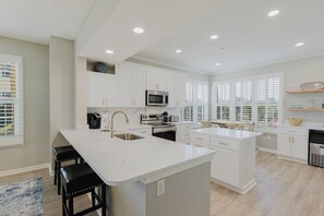 A modern kitchen with white cabinetry, stainless steel appliances, and a large island. - 106E ~ Bright 3BR/3BA beautiful corner condo! (Gulf Shores)