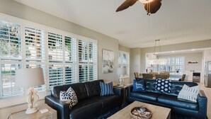 A spacious living room with a black leather sofa, a wooden coffee table, and a patterned rug.