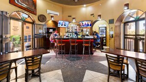 A bar area with stools, a counter, and a television screen.