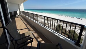A balcony with a view of a beach, a table with chairs, and a railing. - "Breakers East 601"~Gulf Front~2BR/2BA~END UNIT Beach setup included (Destin)