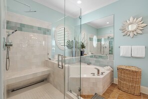 Ein modernes Badezimmer mit einer gläsernen Duschkabine, einer freistehenden Badewanne und einem großen Spiegel mit Sonnendesign.