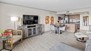 A modern living room with a TV, dining area, and kitchen. - 120- Walkout Balcony to Pool or Beach, Entirely Remodeled, FREE beach service (Destin)