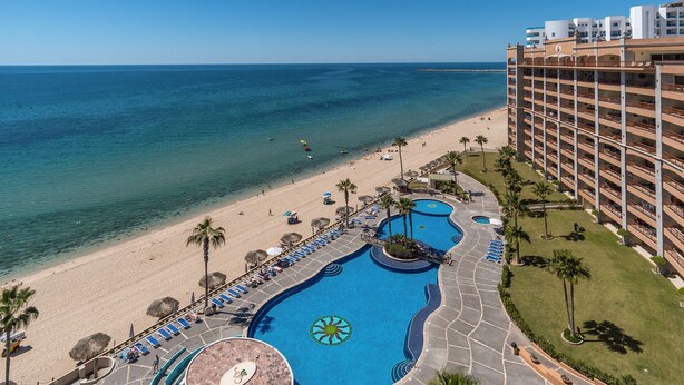 Un resort con una grande piscina, spiaggia e vista sull'oceano.