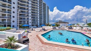 A swimming pool area with lounge chairs and umbrellas, surrounded by a high-rise building with balconies. - 2 Free Beach SRVCS- 4 chairs/2 umbrellas! Free Beach Bonfires M/F nts (Miramar Beach)