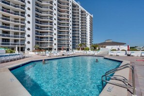 A swimming pool with lounge chairs and a high-rise building in the background. - 2 Free Beach SRVCS- 4 chairs/2 umbrellas! Free Beach Bonfires M/F nts (Miramar Beach)
