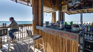 A bar area with a view of the ocean, a television mounted on the wall, and a sign indicating it is a service area only. - 2 Free Beach SRVCS- 4 chairs/2 umbrellas! Free Beach Bonfires M/F nts (Miramar Beach)