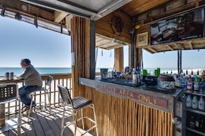 Eine Bar mit Meerblick, einer Theke und einem Fernsehbildschirm.